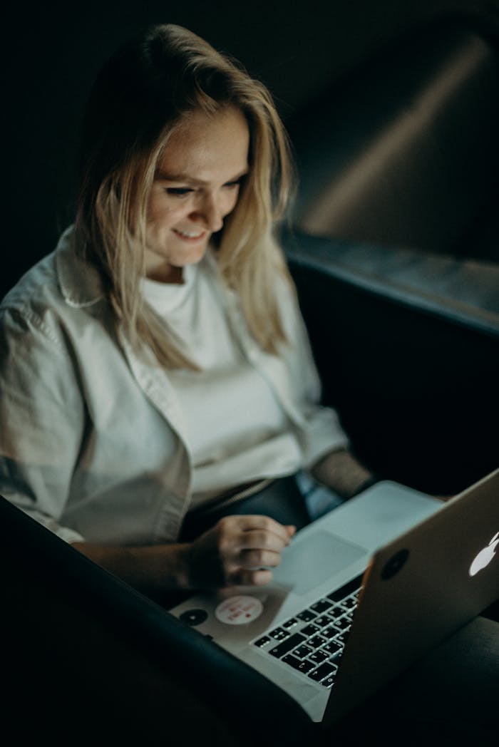 Smiling woman using a laptop indoors for work or leisure in a relaxed environment.